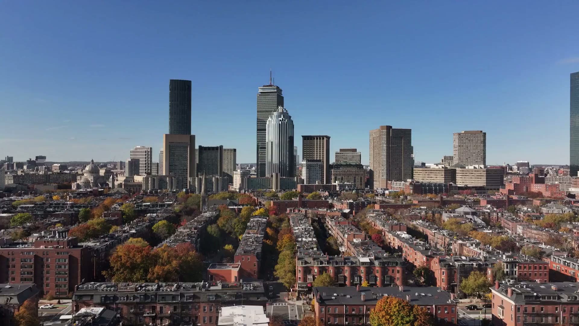 Golden-hour aerial over Back Bay brownstones toward the Boston skyline