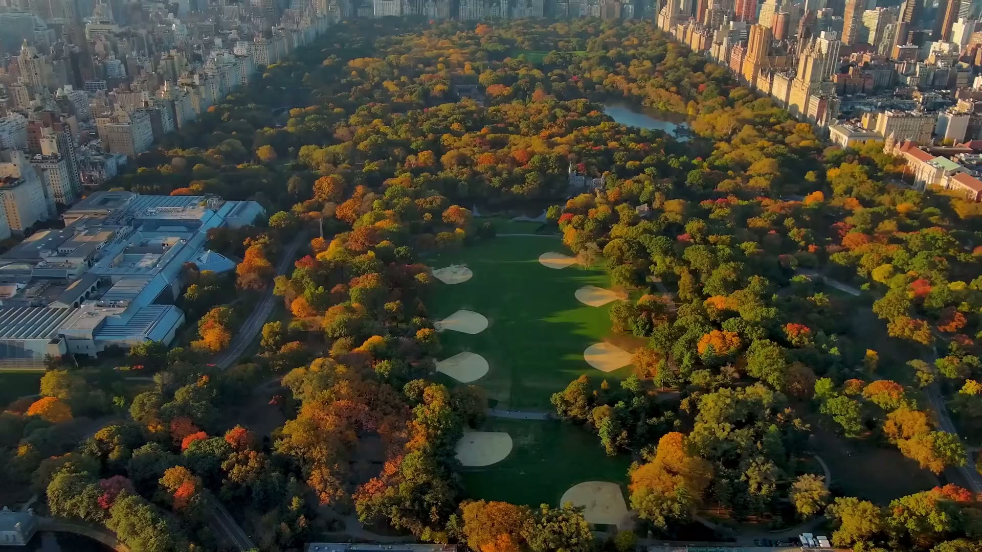 Aerial over Central Park at golden hour with the Manhattan skyline beyond